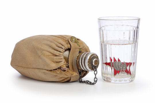 Glass with vodka and khaki textile covered fask isolated on white background