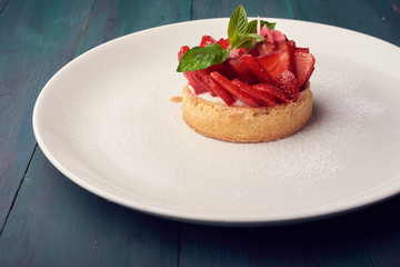 Fresh baked homemade pie with strawberries and whipped cream and cinnamon on white plate. close-up. top or overhead view