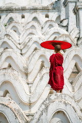 Myanmar Bagan  Novice monk buddhist holding red umbrella  standing on the white pagoda in Bagan Mandalay this is culture in rural of Bagan.
