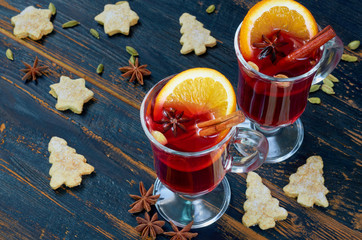 Mulled wine in the glasses with various winter spices - cinnamon, cardamom and anise on the black...