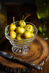 Wild pear in a glass bowl on a wooden dark background. Rustic concept