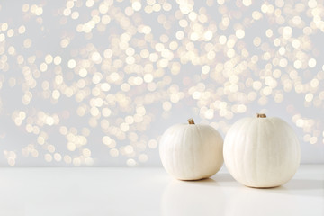 Modern autumn styled composition with white pumkins and golden sparkling bokeh lights. Halloween,...