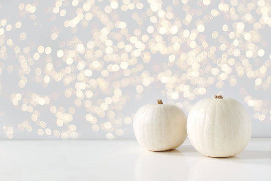 Modern autumn styled composition with white pumkins and golden sparkling bokeh lights. Halloween, Thanksgiving party concept. Festive fall design. - Powered by Adobe
