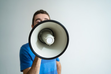 Man holding megaphone in front of his face. Closeup view of loudspeaker. Advertisement concept....