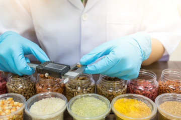 The hand of the quality control officer is using vernier caliper measured kibble size to control quality. Quality control process in pet food industry. Variety of Raw material. © Satawat