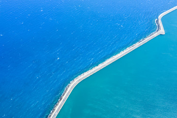 sea of different shades separated by a concrete dam