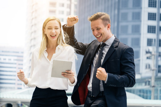 Happy business man and woman congrats together with tablet in hand