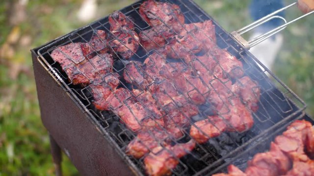 Flip the grill with barbecue meat. 4k slow motion 60fps. Open-air barbecue, juicy meat on the grill. hot coals and fumes.