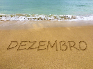 December written in the sand on a beautiful Brazilian beach (translation portuguese: december).