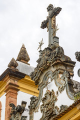 Fototapeta na wymiar Baroque style crucifix on top of ancient and historical church in the city of Sabara in Minas Gerais