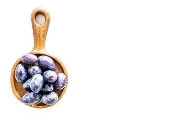Plums on dinning table. Fresh raw purple plum in wooden bowl on white background top view space for text