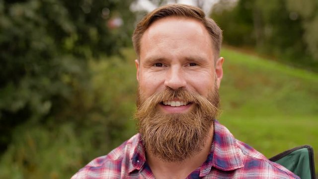 people, emotion and facial expression concept - portrait of happy smiling man with beard