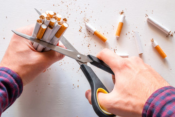 smoker cuts cigarettes with scissors