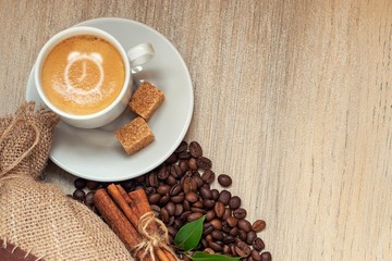 Cup with espresso with coffee beans, burlap sack, cinnamon alarm clock sign on light wooden background
