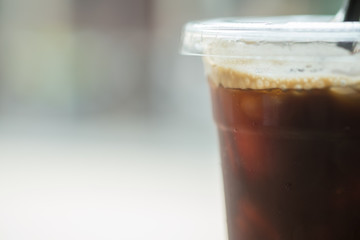 Close up of take away plastic cup of iced black coffee (Americano) with drop.