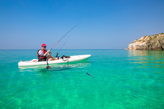 Fishing kayak in the sea on the islands. Man fisherman catch a fish with rod in the boat. Leisure activities on the water.
