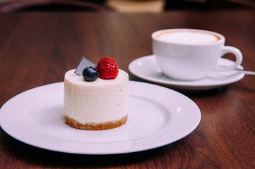 Creamy cheesecake with raspberry and blueberry on white dish in bekery cafe