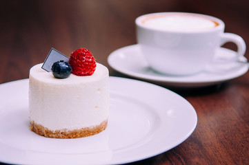 Creamy cheesecake with raspberry and blueberry on white dish in bekery cafe