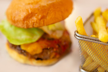 Blurred Big Tasty American Burger And Fries Potatoes On White Table. Fast And Unhealthy Food, Problem Of Healthy Eating Concept.