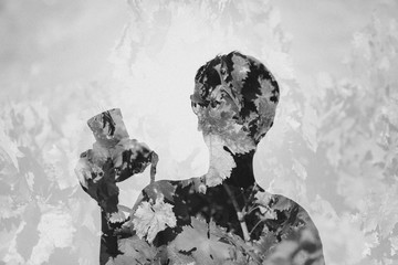 Conceptual double exposure portrait of woman holding a camera in the hand mixed with plant leaves.