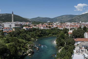 Fototapeta na wymiar Bosnia: lo skyline di Mostar, la città che prende il nome dai guardiani del ponte (mostari) che nel medioevo custodivano lo Stari Most (Ponte Vecchio), visto dalle acque verdi del fiume Narenta