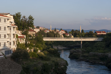 Fototapeta na wymiar Bosnia: lo skyline di Mostar, la città che prende il nome dai guardiani del ponte (mostari) che nel medioevo custodivano lo Stari Most (Ponte Vecchio), visto dalle acque verdi del fiume Narenta
