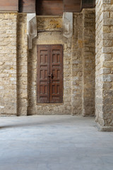 Fototapeta na wymiar Facade of old abandoned stone bricks wall with grunge weathered wooden door, Old Cairo, Egypt