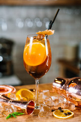 Orange cocktail with lemon and ice in glass at the bar background