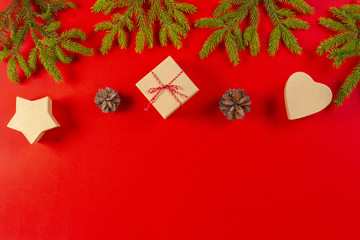 Fototapeta na wymiar Christmas composition. Fir tree branches, pine cones and present gift boxes on red background