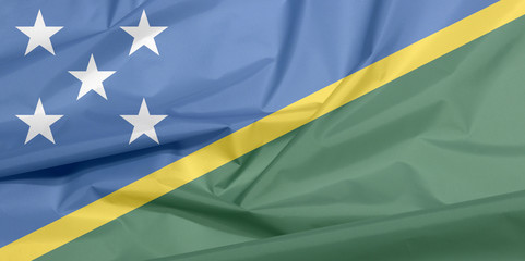 Fabric flag of Solomon Islands. Crease of Solomon flag background, A thin yellow narrow diagonal stripe divided diagonally with green and blue triangle and star.