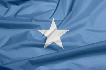 Fabric flag of Somalia. Crease of Somalian flag background, a single white five-pointed star centered on a light blue field.