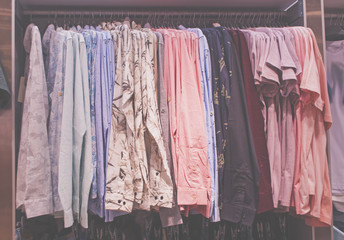 Pastel colored shirts on hangers in a fashion store in shopping mall.