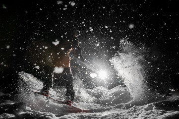 Snowboarder riding on a background of headlight and falling snow