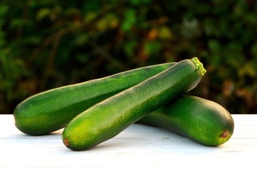 Fresh zucchini on white wooden table on garden background close up.