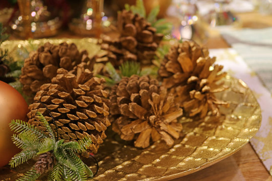 Many Ornamental Dry Pine Cones on the Gold Color Plate for Seasonal Decoration 