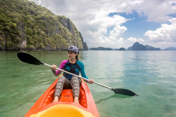 Woman paddling a kayak in the island mountains. Kayaking in El Nido, Palawan, Philippines.