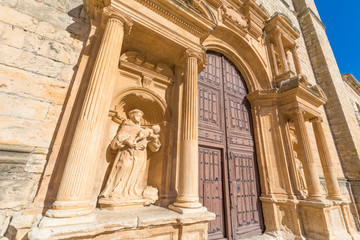 monk with child in arms statue in baroque exterior door of Parish of Santa Ana, landmark and monument in Penaranda de Duero, Burgos, Castile and Leon, Spain, Europe