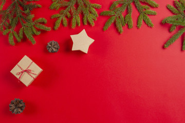 Christmas composition. Fir tree branches, pine cones and present gift boxes on red background