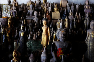 small buddhist statues in a cave around the town with a gold piece