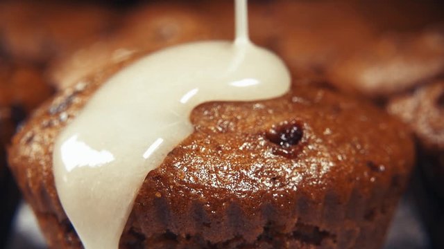 Slow motion chocolate muffins pour white glaze sugar close up
