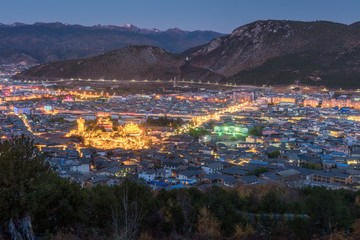 Shangri-la city with Zhongdian temple aerial view and mountain range background during twilight time in Yunan province, China