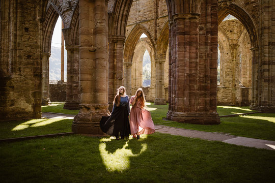 tow women in long dresses in an old abandoned welsh trintern celtic abby