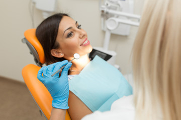 Fototapeta na wymiar Pretty girl having mouth checkup in hospital by professional female dentist