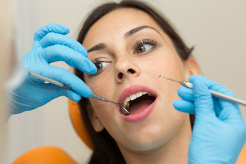 Fototapeta premium Pretty girl having mouth checkup in hospital by professional female dentist