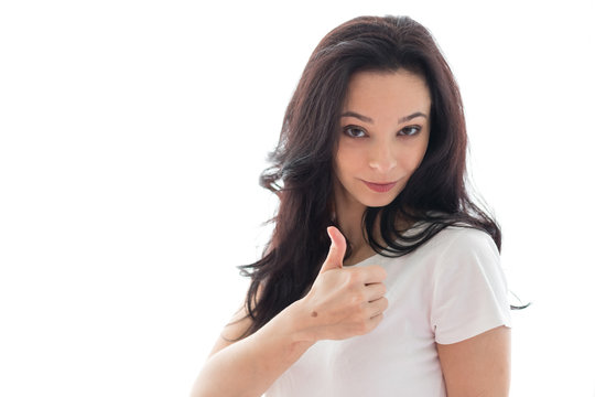 Caucasian girl with long dark hair expresses emotions of approval having raised a hand thumb up. The girl in light clothes on a white background. The place for an inscription or the text. Horizontal 
