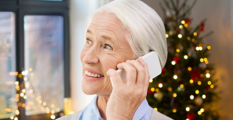 technology, holidays and people concept - happy senior woman with smartphone calling at home over...