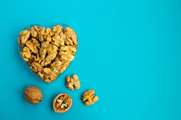 Walnuts in the heart shape  on the blue background.Top view.Copy space.