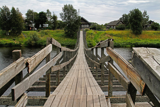 Old wooden suspension bridge over the river in the village