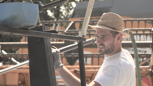 The mechanics repair the blue combine harvester in the farm yard. 