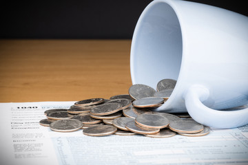 U.S. INDIVIDUAL INCOME TAX RETURN - FORM 1040 AND A COFFEE CUP WITH BUNCH OF US QUARTER COINS,...